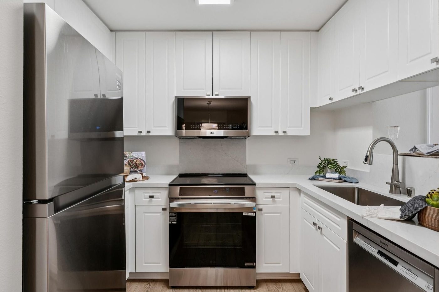 Bright white kitchen with stainless steel appliances and wood floor