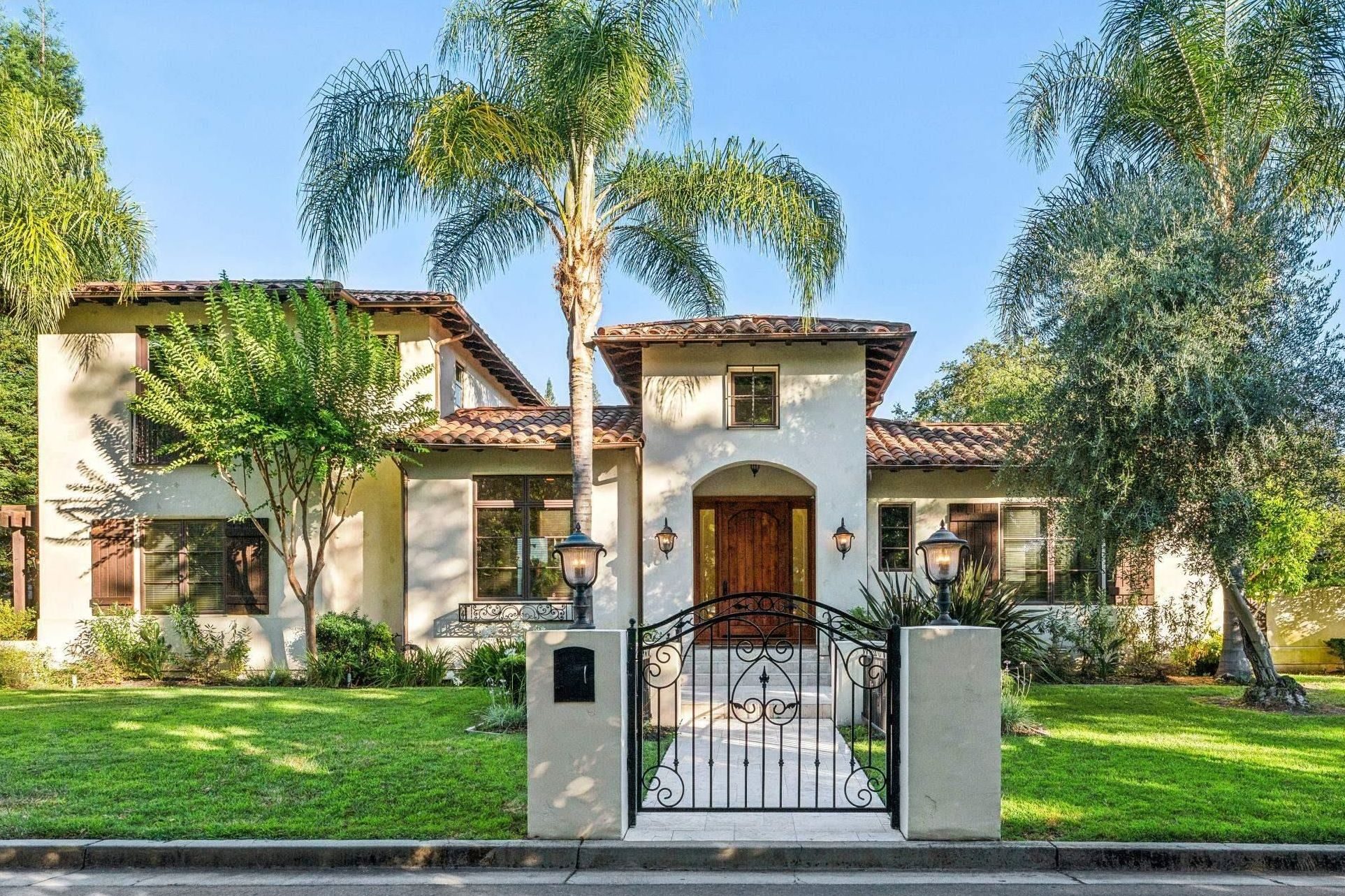 Spanish-style white house with red tile roof and palm trees
