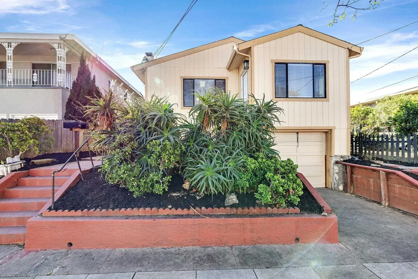 Tan house with raised planter of succulents and steps to entry