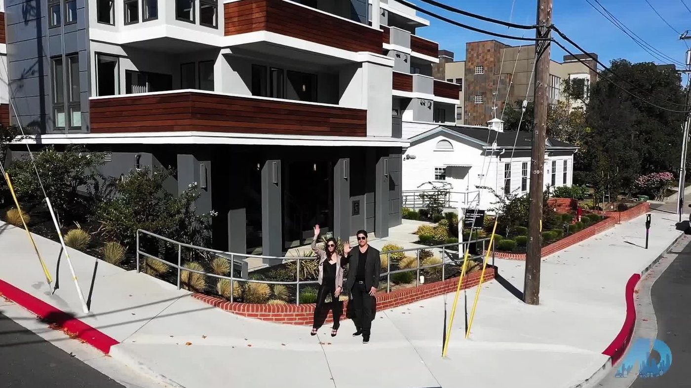 Two people walking past modern apartment building on a sunny day